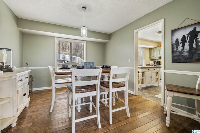 dining area featuring dark wood-style flooring, a textured ceiling, and baseboards