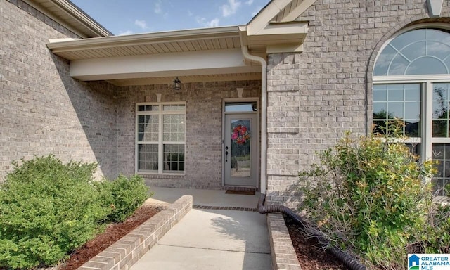 entrance to property with a porch and brick siding