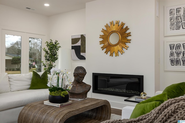 living area featuring a glass covered fireplace, recessed lighting, wood finished floors, and visible vents