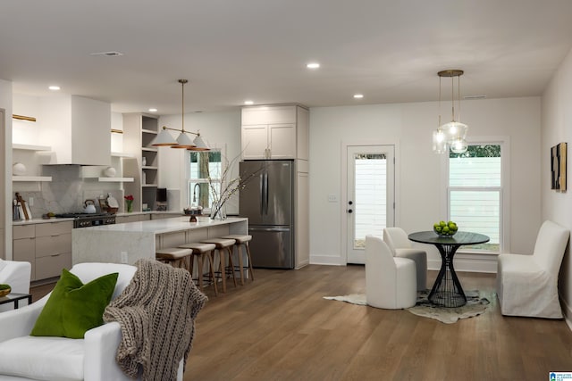 kitchen featuring dark wood-type flooring, open shelves, a kitchen breakfast bar, a center island, and freestanding refrigerator