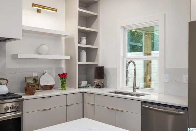 kitchen with a sink, open shelves, appliances with stainless steel finishes, and light countertops