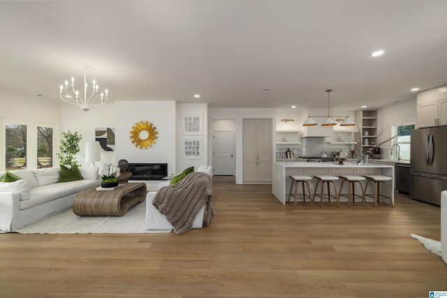 living room featuring light wood finished floors, a chandelier, and recessed lighting