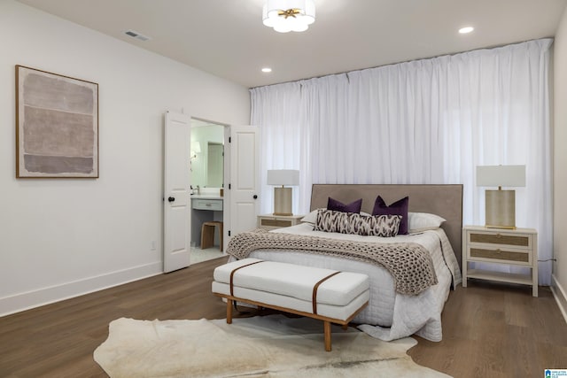 bedroom with wood finished floors, visible vents, baseboards, ensuite bath, and recessed lighting