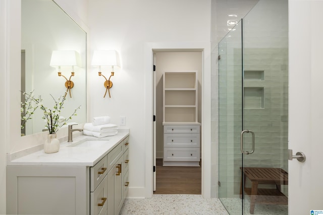 full bathroom featuring speckled floor, vanity, a walk in closet, and a shower stall