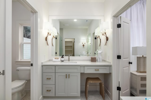 bathroom with visible vents, baseboards, toilet, vanity, and speckled floor