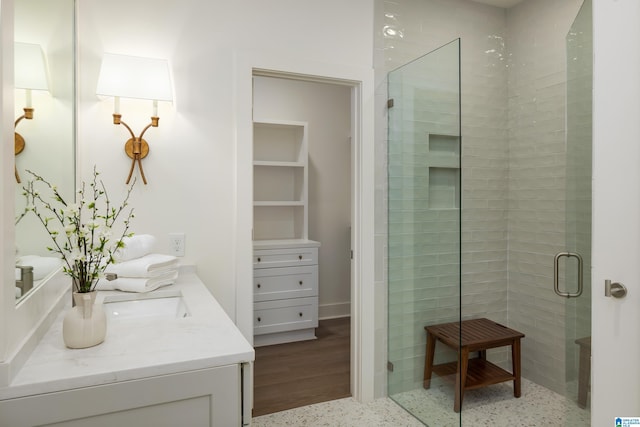 full bath featuring vanity, a shower stall, and speckled floor