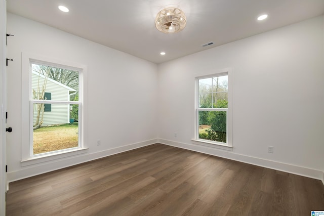 empty room featuring dark wood-type flooring, recessed lighting, visible vents, and baseboards