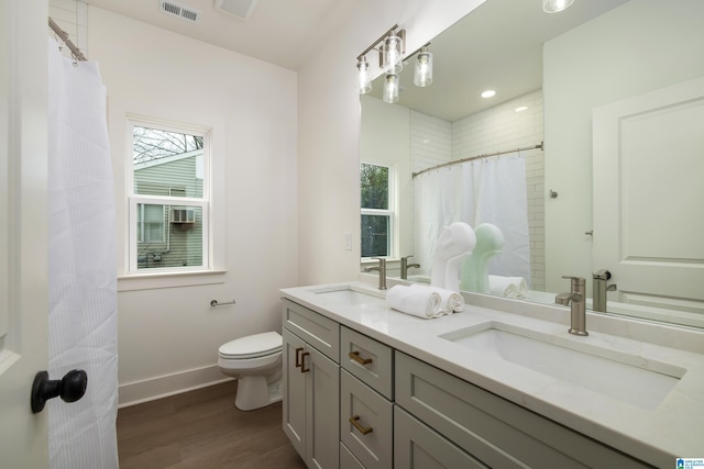 full bath with toilet, a healthy amount of sunlight, visible vents, and a sink