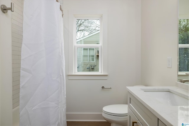 full bath featuring baseboards, plenty of natural light, toilet, and vanity