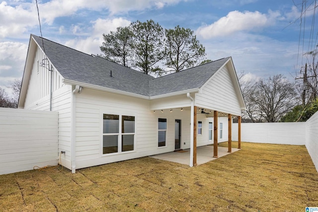 back of property featuring a yard, a patio area, a fenced backyard, and a shingled roof