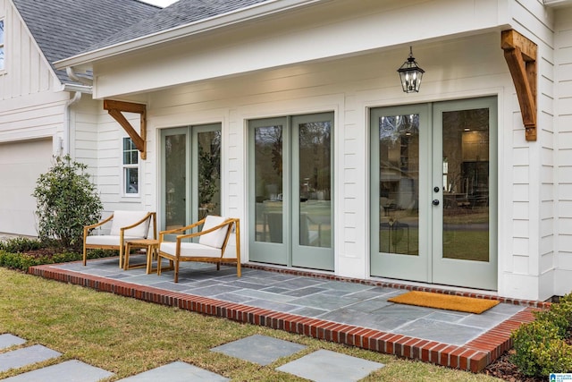 view of exterior entry featuring french doors, board and batten siding, and roof with shingles