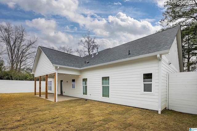 back of house with a yard, a patio, roof with shingles, and fence