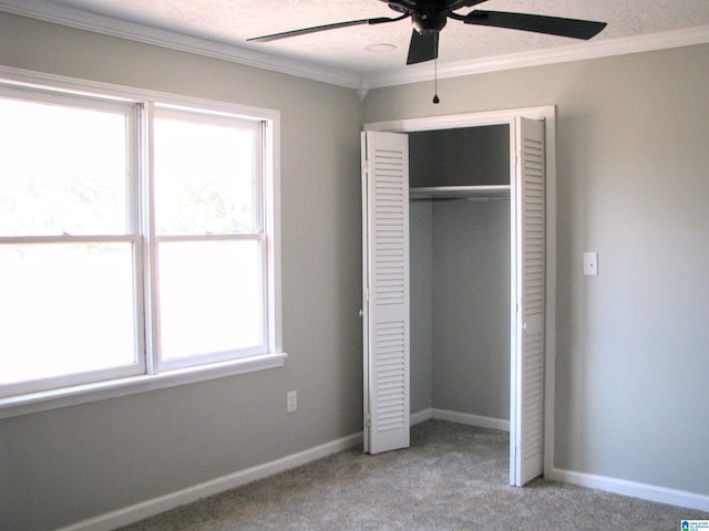 unfurnished bedroom featuring crown molding, carpet floors, multiple windows, and a closet
