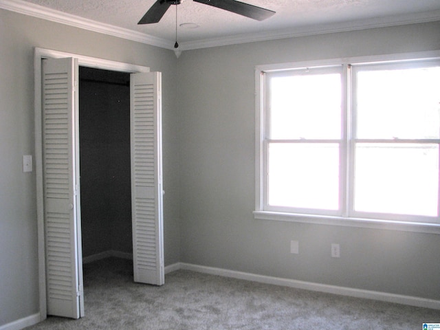 unfurnished bedroom featuring baseboards, a closet, ornamental molding, light carpet, and a ceiling fan