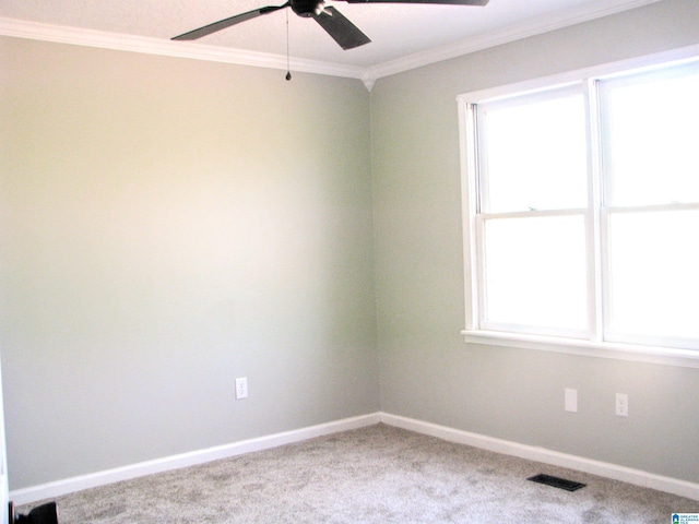 empty room with a wealth of natural light, visible vents, a ceiling fan, and crown molding