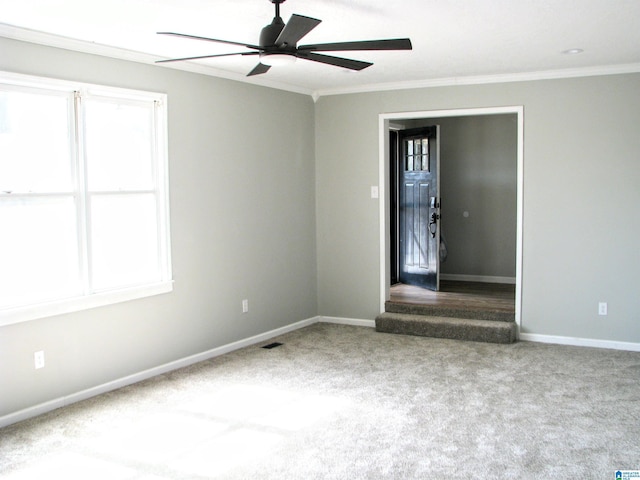 carpeted empty room featuring a ceiling fan, baseboards, ornamental molding, and visible vents