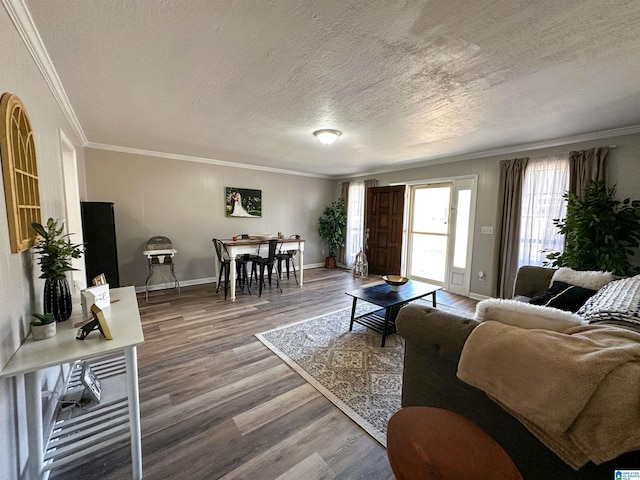 living area with baseboards, a textured ceiling, ornamental molding, and wood finished floors