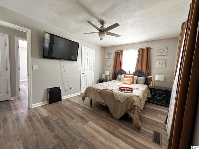 bedroom featuring a textured ceiling, visible vents, and wood finished floors