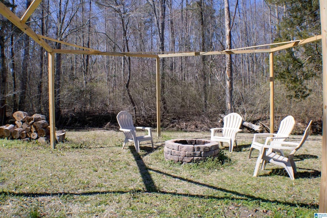 view of yard with an outdoor fire pit and a wooded view