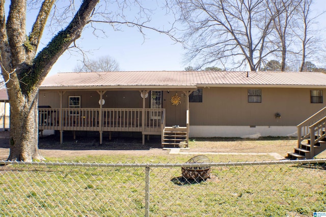 rear view of property featuring crawl space, an outdoor fire pit, fence, and a deck