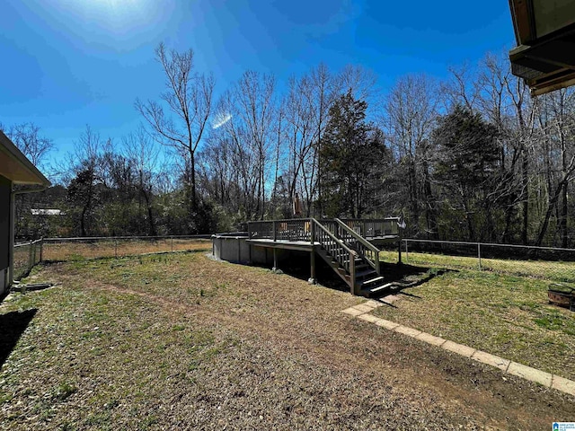 view of yard featuring fence, a wooden deck, and stairs