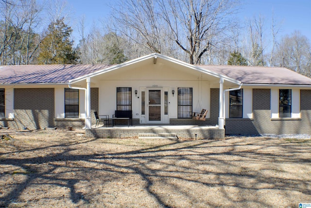 view of front of house with covered porch, metal roof, and brick siding