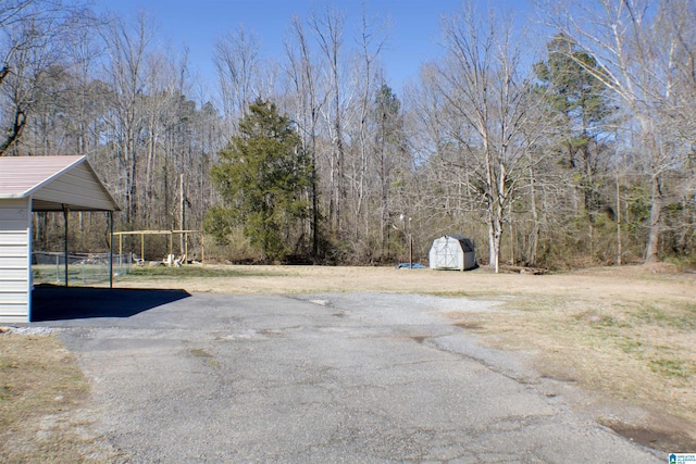 view of yard with a shed, a view of trees, and an outdoor structure