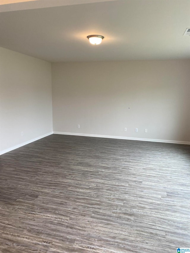 empty room with visible vents, dark wood-style floors, and baseboards