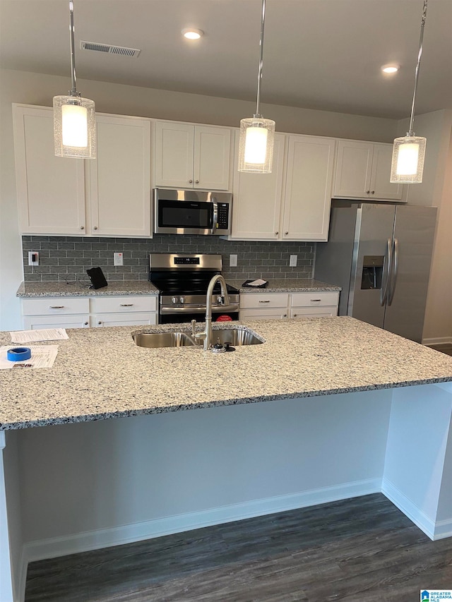 kitchen featuring visible vents, a sink, stainless steel appliances, white cabinetry, and tasteful backsplash