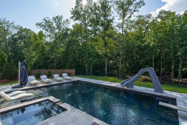 view of pool featuring a water slide, a fenced backyard, a pool with connected hot tub, a patio area, and a lawn