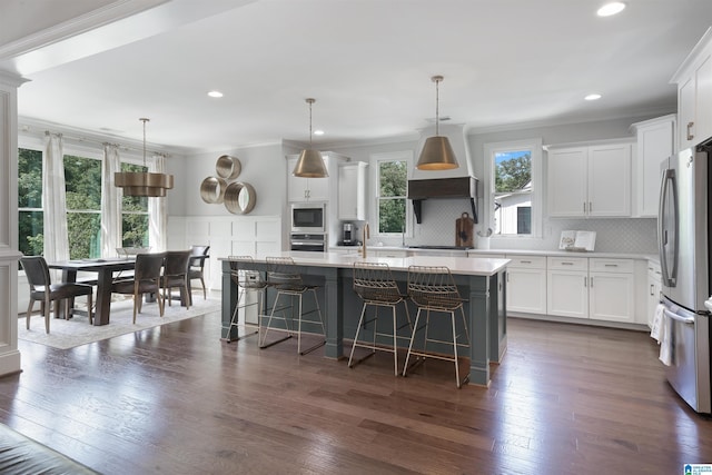 kitchen featuring light countertops, a breakfast bar area, crown molding, and stainless steel appliances