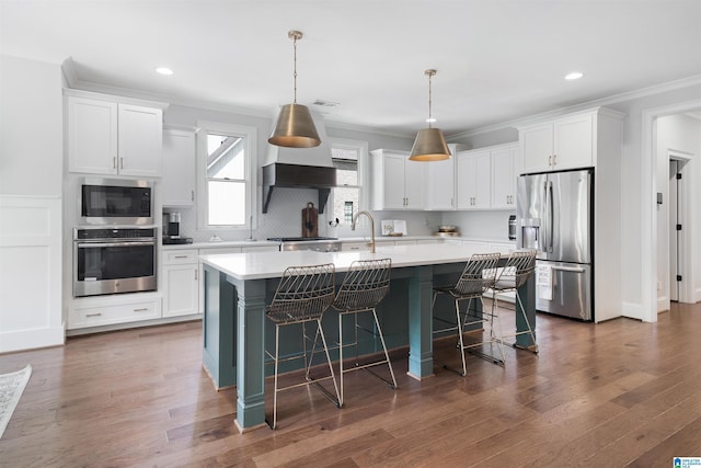 kitchen featuring an island with sink, appliances with stainless steel finishes, white cabinetry, and light countertops