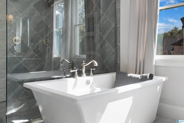 bathroom with a soaking tub and marble finish floor