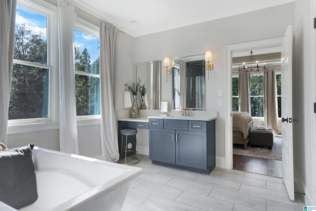 ensuite bathroom with a freestanding bath, vanity, ensuite bathroom, and an inviting chandelier