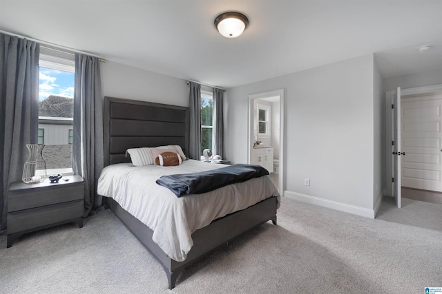 carpeted bedroom with connected bathroom and baseboards