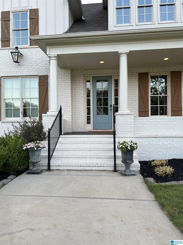 entrance to property featuring brick siding, covered porch, and board and batten siding