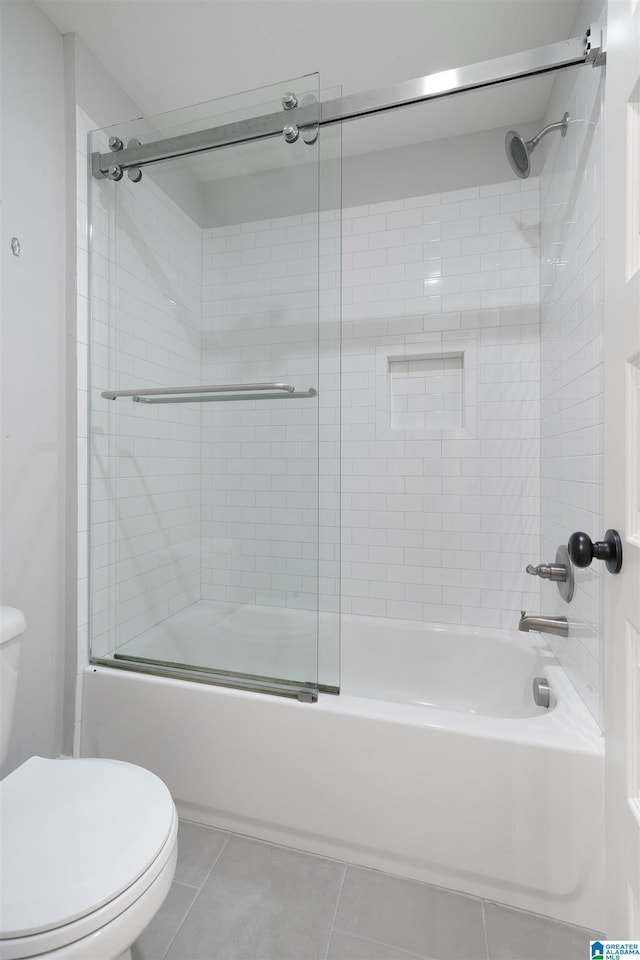 bathroom featuring toilet, shower / bath combination with glass door, and tile patterned flooring