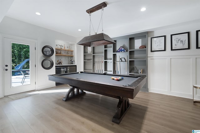 game room featuring built in features, light wood-type flooring, billiards, and a decorative wall