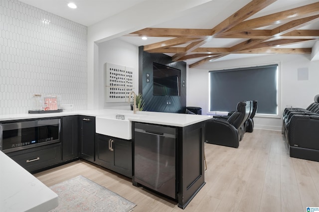 kitchen featuring dark cabinetry, appliances with stainless steel finishes, open floor plan, and light wood finished floors