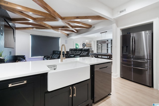 kitchen with open floor plan, beamed ceiling, light countertops, appliances with stainless steel finishes, and dark cabinets