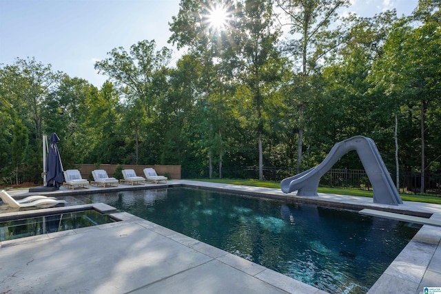 view of pool featuring a patio, fence, a fenced in pool, a water slide, and a diving board