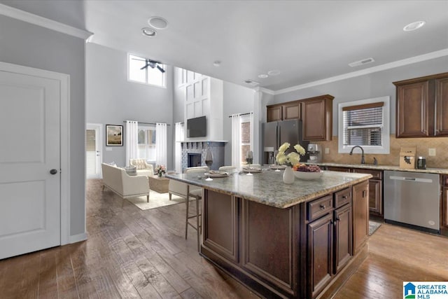 kitchen with appliances with stainless steel finishes, a fireplace, a sink, and wood-type flooring