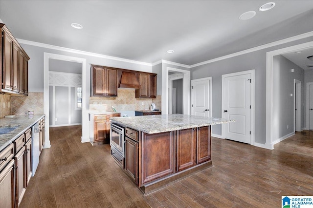 kitchen featuring stainless steel appliances, premium range hood, dark wood-type flooring, and baseboards