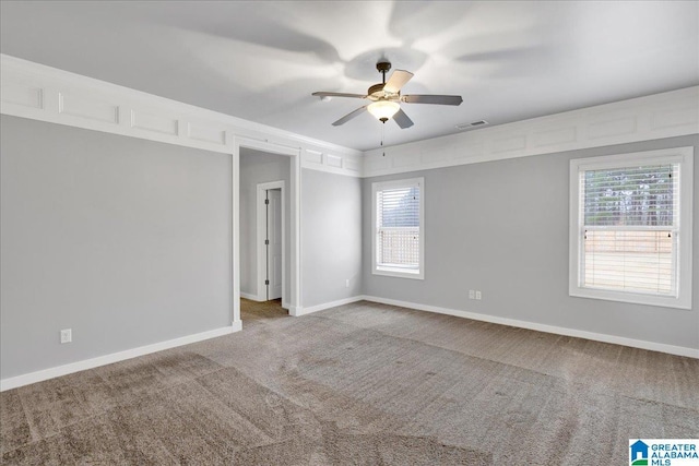 empty room featuring plenty of natural light, carpet, visible vents, and ceiling fan