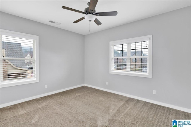 carpeted empty room featuring baseboards, visible vents, and a ceiling fan