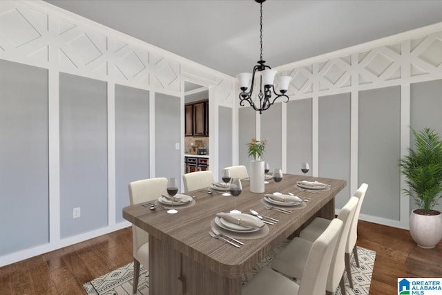 dining space with dark wood finished floors, a notable chandelier, and a decorative wall