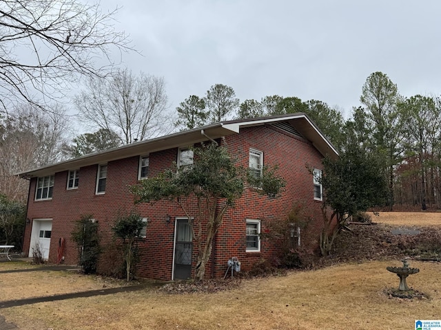 view of side of home featuring brick siding, a yard, and an attached garage