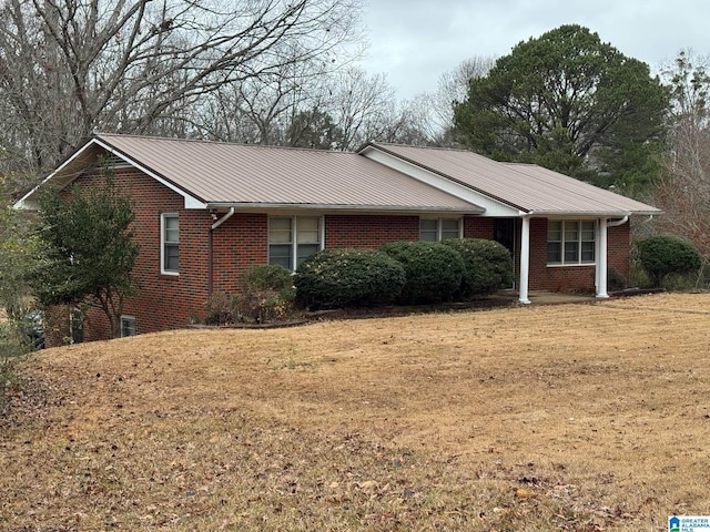 single story home with brick siding, metal roof, and a front lawn