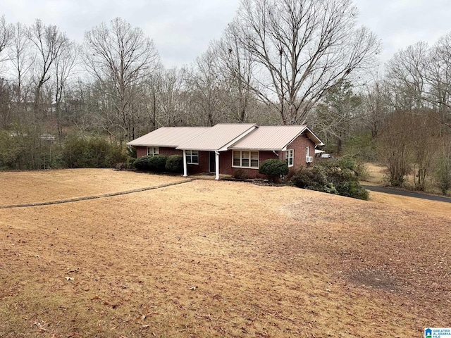 single story home featuring metal roof and brick siding