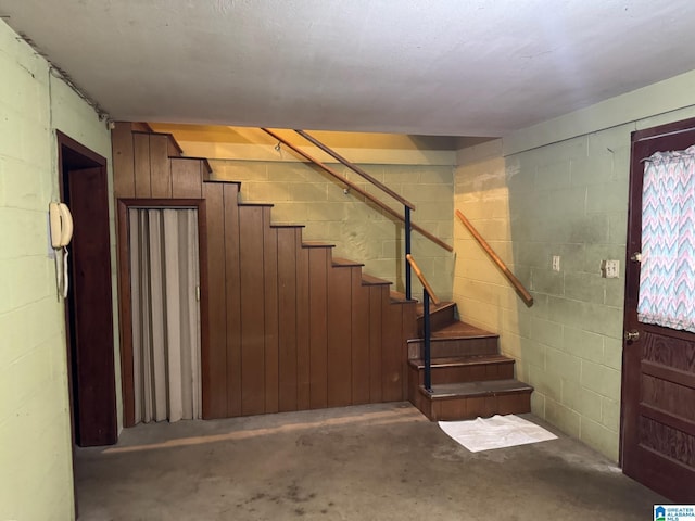 stairway featuring concrete floors and concrete block wall